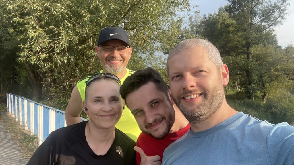 dwóch mężczyzn i jedna kobieta w strojach sportowych pozują na na moście